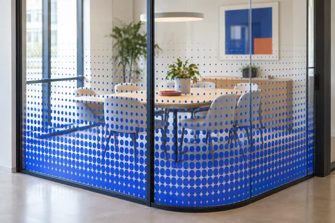 Illustrative meeting room enclosed by blue dot-gradient privacy glass.